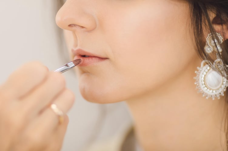 Woman applying lipstick as part of a beauty routine